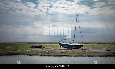 Le barche si trovano arenate sull'estuario del Tamigi con la bassa marea a Leigh-on-Sea, Essex, Regno Unito. Foto Stock