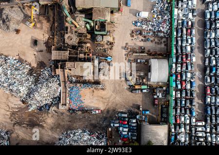 Una vista aerea direttamente sopra un rottame o un cantiere di riciclaggio e rottamazione danneggiati e cancellare auto e veicoli. Foto Stock