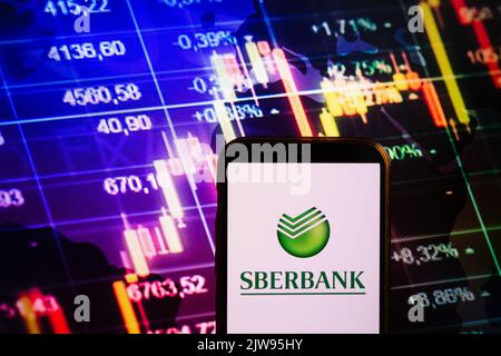 KONSKIE, POLONIA - 30 agosto 2022: Smartphone che mostra il logo della società Sberbank sullo sfondo del diagramma di borsa Foto Stock