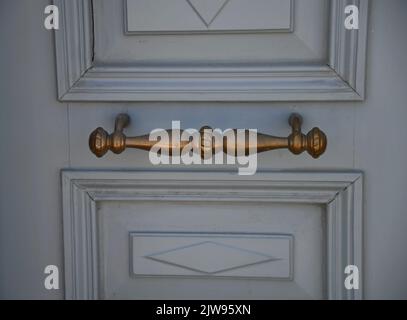 Vecchia casa neoclassica porta d'ingresso in legno grigio con un antico manico in ottone. Foto Stock