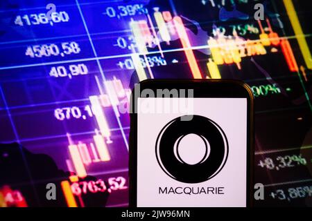 KONSKIE, POLONIA - 30 agosto 2022: Smartphone che mostra il logo della società Macquarie sullo sfondo del diagramma di borsa Foto Stock