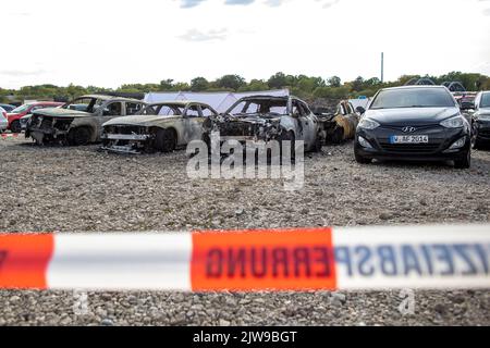 Duisburg, Germania. 04th Set, 2022. I veicoli bruciati si trovano in un parcheggio di fronte alla tenda del circo FlicFlac dopo che un piccolo aereo si è schiantato lì. Due persone sono state uccise quando il piccolo aereo si è schiantato vicino all'autostrada A59 vicino a Duisburg. Credit: Christoph Reichwein/dpa/Alamy Live News Foto Stock