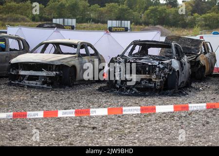 Duisburg, Germania. 04th Set, 2022. I veicoli bruciati si trovano in un parcheggio di fronte alla tenda del circo FlicFlac dopo che un piccolo aereo si è schiantato lì. Due persone sono state uccise quando il piccolo aereo si è schiantato vicino all'autostrada A59 vicino a Duisburg. Credit: Christoph Reichwein/dpa/Alamy Live News Foto Stock