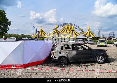 Duisburg, Germania. 04th Set, 2022. I veicoli bruciati si trovano di fronte alla tenda del circo FlicFlac dopo che un piccolo aereo si è schiantato lì; il luogo dell'incidente è circondato da una protezione visiva. Due persone sono morte nel crollo del piccolo aereo vicino all'autostrada A59 vicino a Duisburg. Credit: Christoph Reichwein/dpa/Alamy Live News Foto Stock