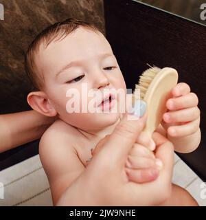 La madre insegna a pettinare i capelli ad un bambino felice del bambino del bambino. Mamma fa un acconciatura con un bambino sorridente. Bambino di un anno Foto Stock