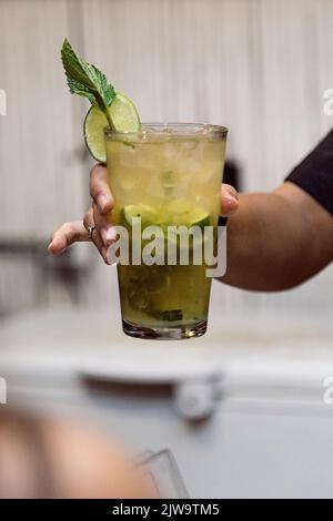 Barista che mostra al cliente la bevanda che ha appena preparato. Atmosfera da night club o da festa. Bevande di classe. Vita notturna Foto Stock