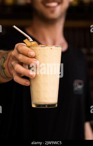 Barista che mostra al cliente la bevanda che ha appena preparato. Atmosfera da night club o da festa. Bevande di classe. Vita notturna Foto Stock