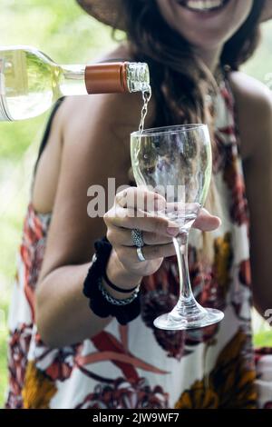 Donna che tiene un bicchiere mentre viene servito vino. Atmosfera rilassata. All'aperto Foto Stock