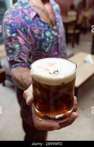 Barista che mostra al cliente la bevanda che ha appena preparato. Atmosfera da night club o da festa. Bevande di classe. Vita notturna Foto Stock