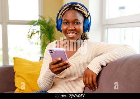 donna ispanica latina ascoltare musica mentre si siede sul divano in soggiorno Foto Stock