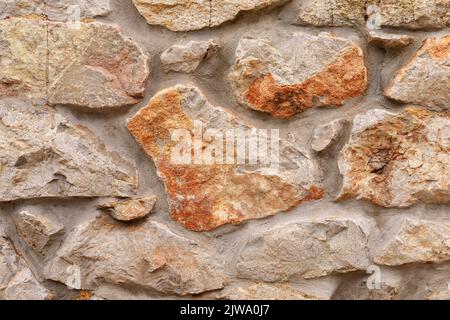 Muro di pietra con struttura ruvida e ruvida superficie ruvida di primo piano marrone. Sfondo astratto naturale Foto Stock