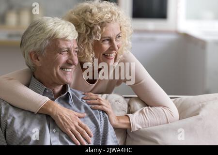 Felice coppia matura allegra attraente in amore abbracciare sul divano Foto Stock