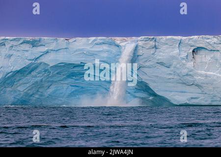 un fiume blu ghiacciato attraversa la calotta di ghiaccio austfonna sul nordaustlandet e si schianta verso il mare, sulla scogliera di ghiaccio a picco, come un'enorme cascata Foto Stock