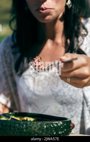 Donna che mangia riso con fagioli. Sta tenendo in mano una forchetta e la sta puntando alla bocca. Atmosfera tropicale Foto Stock