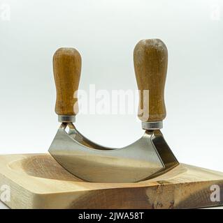 primo piano di un attrezzo di taglio da cucina a 2 pale e di una tavola di legno Foto Stock