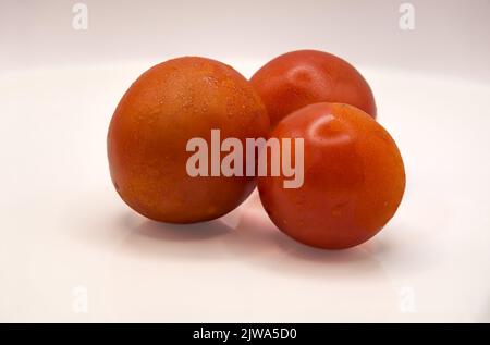 dettaglio primo piano di tre pomodori maturi scintillanti Foto Stock