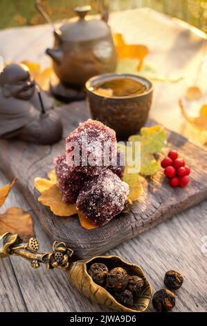 Marmellata di frutta e tè cinese in un autunno ancora vita. Originale cucchiaio di bronzo a forma di fiore con legato tè secco e una tazza di tè. Autunno st Foto Stock