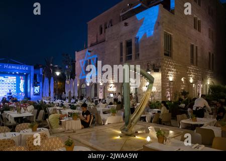 La gente siede fuori ristoranti di notte in Kikar HaMusica (Piazza della Musica) un complesso con palco di spettacolo all'aperto situato nel quartiere Nahalat Shiva nel centro di Gerusalemme Israele Foto Stock