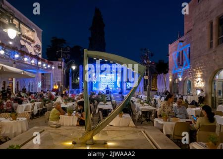 La gente siede fuori ristoranti di notte in Kikar HaMusica (Piazza della Musica) un complesso con palco di spettacolo all'aperto situato nel quartiere Nahalat Shiva nel centro di Gerusalemme Israele Foto Stock