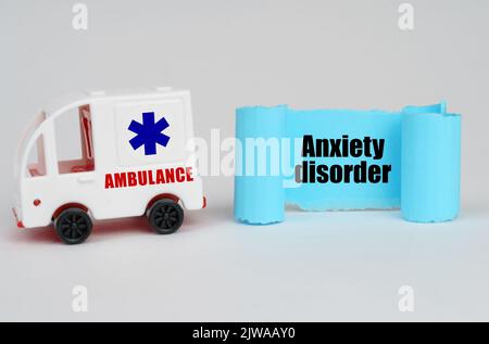 Su una superficie bianca, un'ambulanza e un segno di carta blu con l'iscrizione - disturbo d'ansia Foto Stock