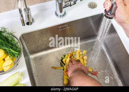 Riciclaggio dei rifiuti alimentari con un dispositivo di smaltimento nel lavello della cucina Foto Stock