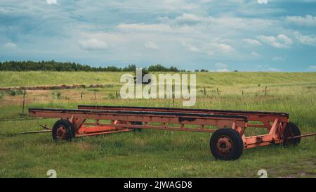 Vecchie parti abbandonate di un rimorchio per autocarri con ruote al centro del campo agricolo Foto Stock