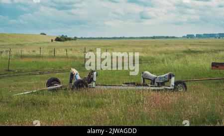 Vecchie parti abbandonate di un rimorchio per autocarri con ruote al centro del campo agricolo Foto Stock