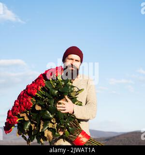 Uomo con bouquet di fiori di rose. L'uomo tiene un grande bouquet di rose rosse, proporre al fidanzato in data. Romantico ragazzo celebrare San Valentino. Foto Stock
