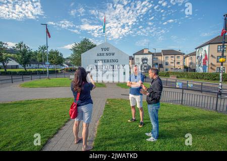 Segno che entra nel Derry libero con il murale dagli artisti di Bogside sul lato della casa a Derry, Irlanda del Nord. Foto Stock