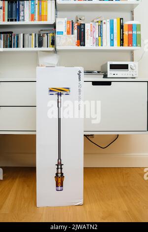 Parigi, Francia - 16 luglio 2022: Nuova confezione in cartone del nuovo aspirapolvere cordless a batteria by Dyson V12 slim Absolute con ripiani in Vitsoe sullo sfondo con sistema audio Onkyo a destra Foto Stock