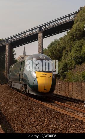 Teignmouth, Devon, Inghilterra, Regno Unito. 2022. Treno passeggeri che si avvicina alla stazione di Teignmouth sotto il ponte pedonale East Cliff. Foto Stock