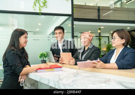 Gruppo di uomini d'affari asiatici che lavorano insieme, in una discussione e sorridendo. Ambiente di lavoro CO. Foto Stock