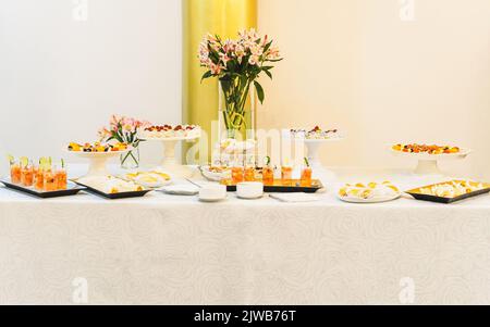 Tavolo buffet con tovaglia con diversi snack salati e dolci Foto Stock