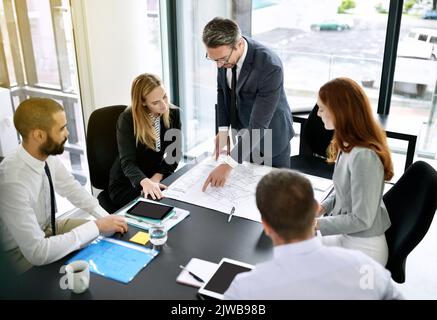 Finalizzazione dei progetti per un nuovo edificio. Un team di architetti che si occupa di un progetto durante una riunione formale in un ufficio. Foto Stock