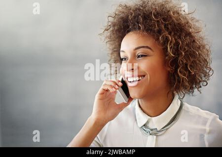 Parlare con un altro cliente soddisfatto. Una giovane donna che parla su un cellulare nel suo ufficio. Foto Stock