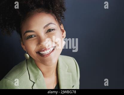 Esprimi te stesso. Foto studio di una giovane donna che si erge su uno sfondo scuro. Foto Stock