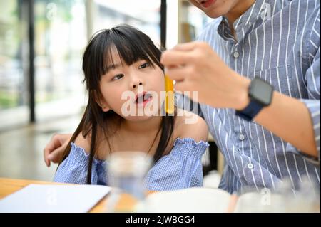 Ragazza asiatica cute giovane che ha tempo di divertimento con il suo papà durante fare esperimento di scienza per il bambino a casa. Foto Stock