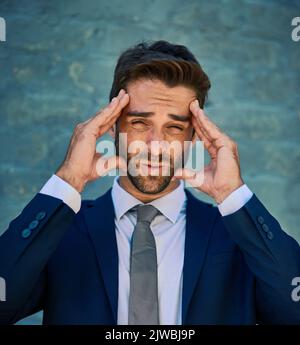 Il business è pieno di alti e bassi. Ritratto di un giovane, tensed che guarda uomo d'affari aziendale in piedi contro un muro di mattoni. Foto Stock