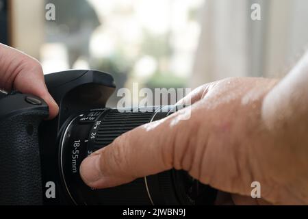 Fotografo maschile che posiziona un obiettivo standard su una fotocamera professionale. Foto Stock