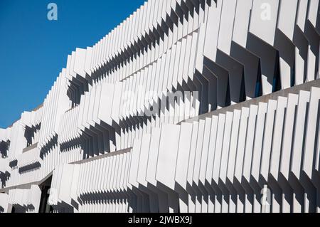 Parte futuristica del design di un edificio su uno sfondo blu chiaro del cielo. Design astratto della facciata. Moderna architettura cittadina. Foto Stock