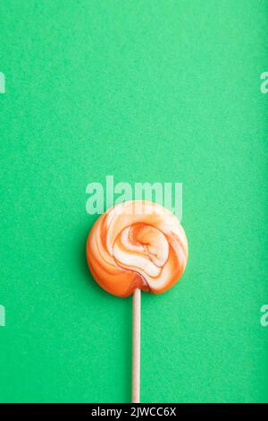 Una caramella a lecca lecca su sfondo pastello verde. Spazio copia, vista dall'alto, disposizione piatta. Foto Stock