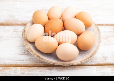 Mucchio di uova di pollo colorate sul piatto su uno sfondo di legno bianco. Vista laterale, primo piano. Foto Stock
