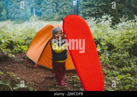 Bambino con imbottitura a pelo famiglia campeggio tenda ingranaggio viaggio avventura vacanze attrezzatura escursionistica all'aperto nella foresta sano stile di vita eco turismo Foto Stock