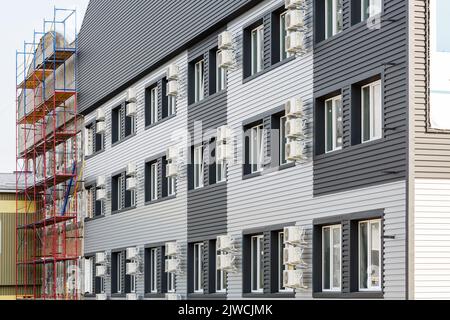 Molti compressori dell'aria condizionata. Edificio moderno in un'area residenziale con molte finestre e aria condizionata nelle vicinanze. Vista laterale del bui bianco-grigio Foto Stock