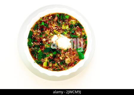 Piatto estivo tradizionale - borscht freddo con uova di patate, erbe aromatiche, ravanello, cetriolo, barbabietola, panna acida. Un piatto di cucina Ucraina, Polacca e russa. Sfondo isolato bianco. Foto Stock