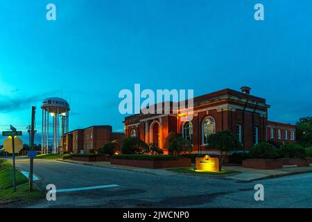 Troy, Alabama, Stati Uniti d'America - 3 settembre 2022: Il municipio di Troy in primo piano con il complesso di utilità di Grady Homer Reeves e la torre dell'acqua nella dur di fondo Foto Stock