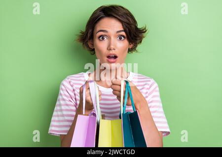 Foto di una donna stupefatto alla moda vestito elegante visitato boutique impressionato numero di vestiti spesi soldi lotto isolato su sfondo di colore verde Foto Stock