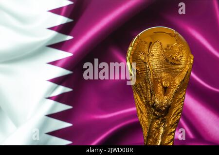 Doha, Qatar - 4 settembre 2022: Trofeo della Coppa del mondo FIFA sullo sfondo della bandiera Qatar. Foto Stock