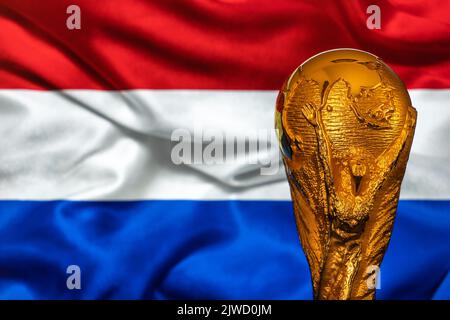 Doha, Qatar - 4 settembre 2022: Trofeo della Coppa del mondo FIFA sullo sfondo della bandiera olandese. Foto Stock