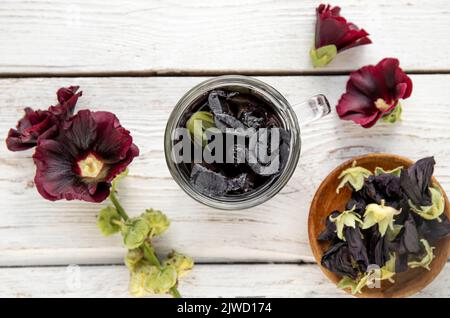 Bevanda a base di erbe medicinali a base di tè fatta di Malva sylvestris L. noto come comune mallow, formaggi, alto mallow e alto mallow. Tazza di vetro con tè bianco. Foto Stock